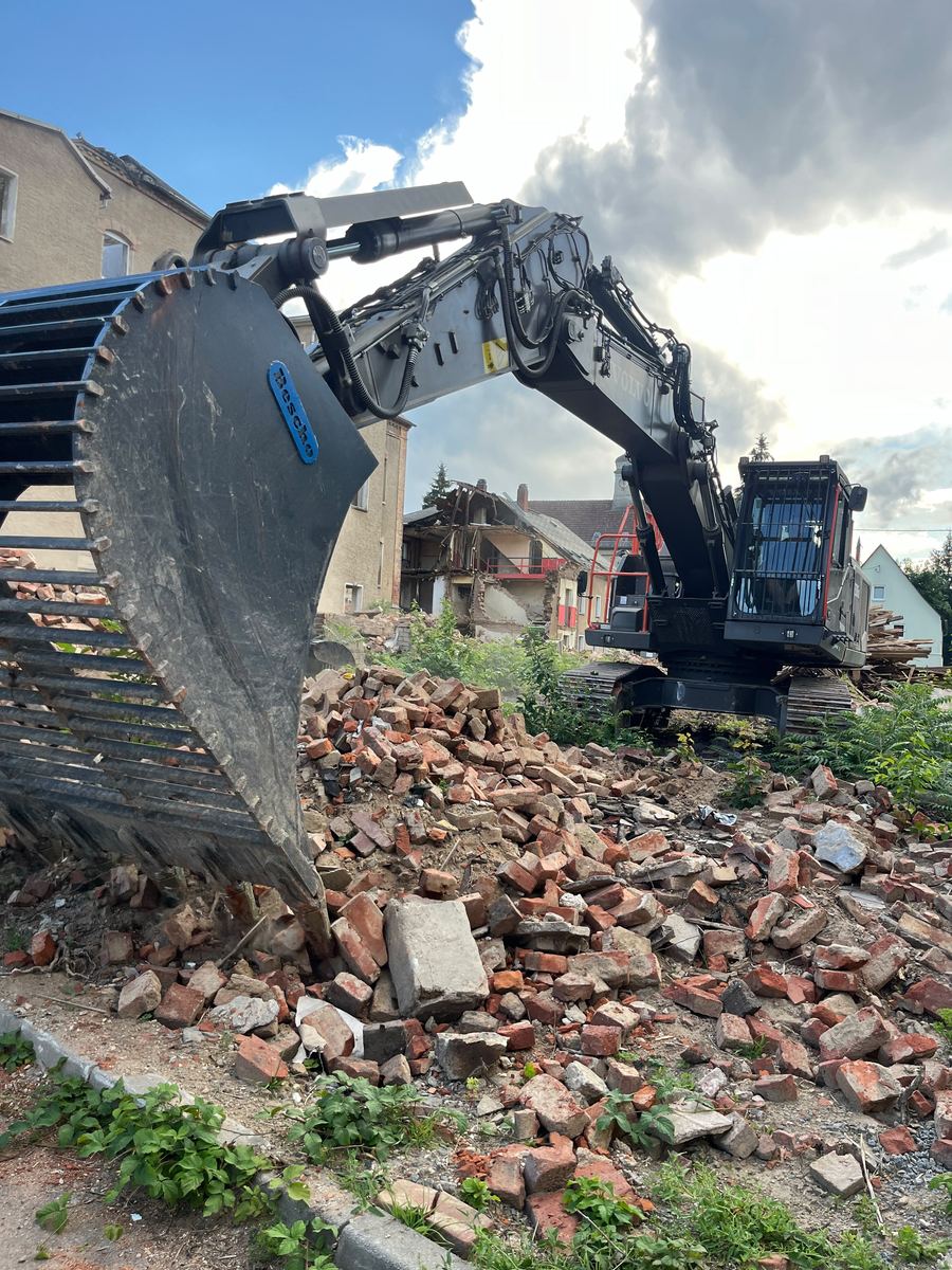 Baggerschaufel vor sortiertem Ziegelschutt eines Abbruchobjekts