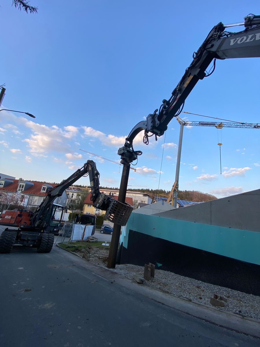 Bagger rammt einen Verbauträger zur Sicherung der Baugrube ein